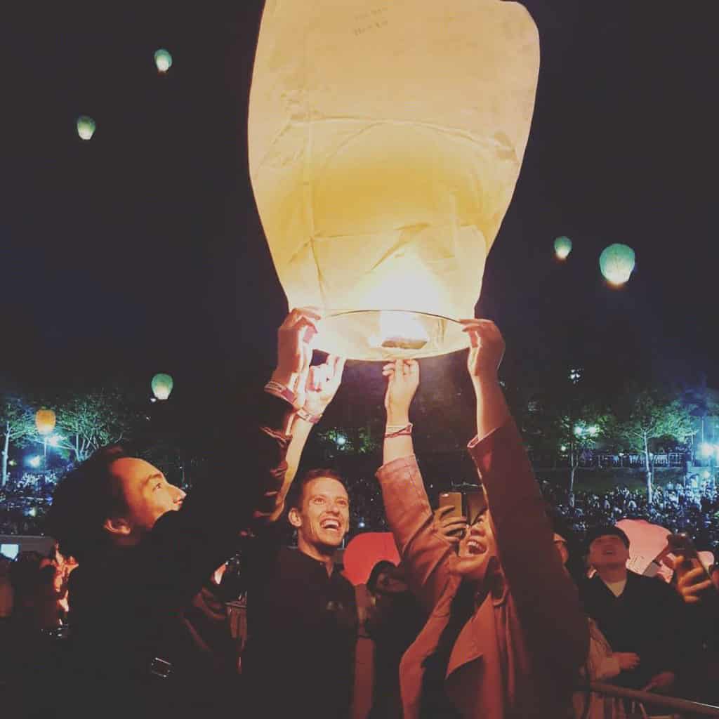 Three smiling people holding an asian style lantern
