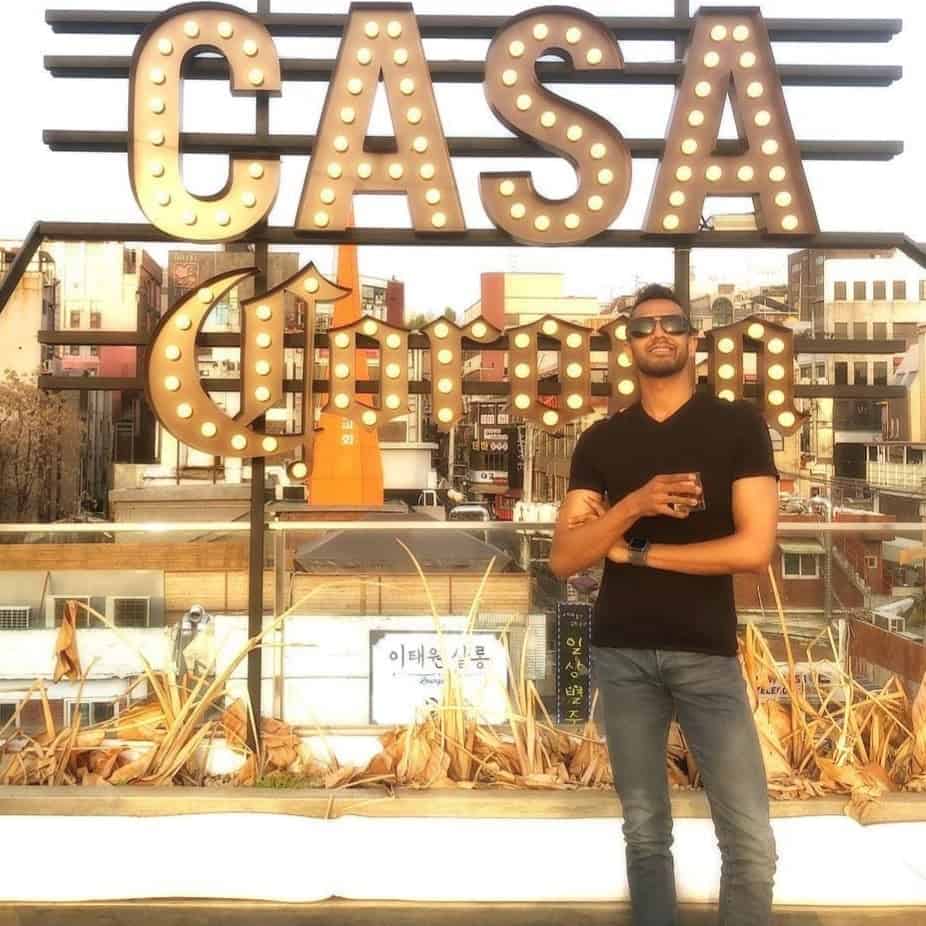 Man holding a drink standing in front of a "Casa Corona" sign