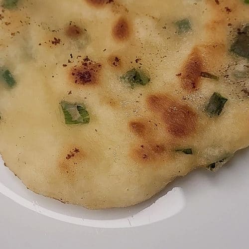 A closeup of fried flatbread with green onions