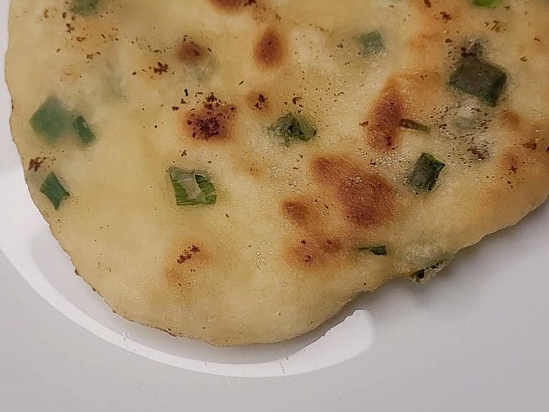 A closeup of fried flatbread with green onions