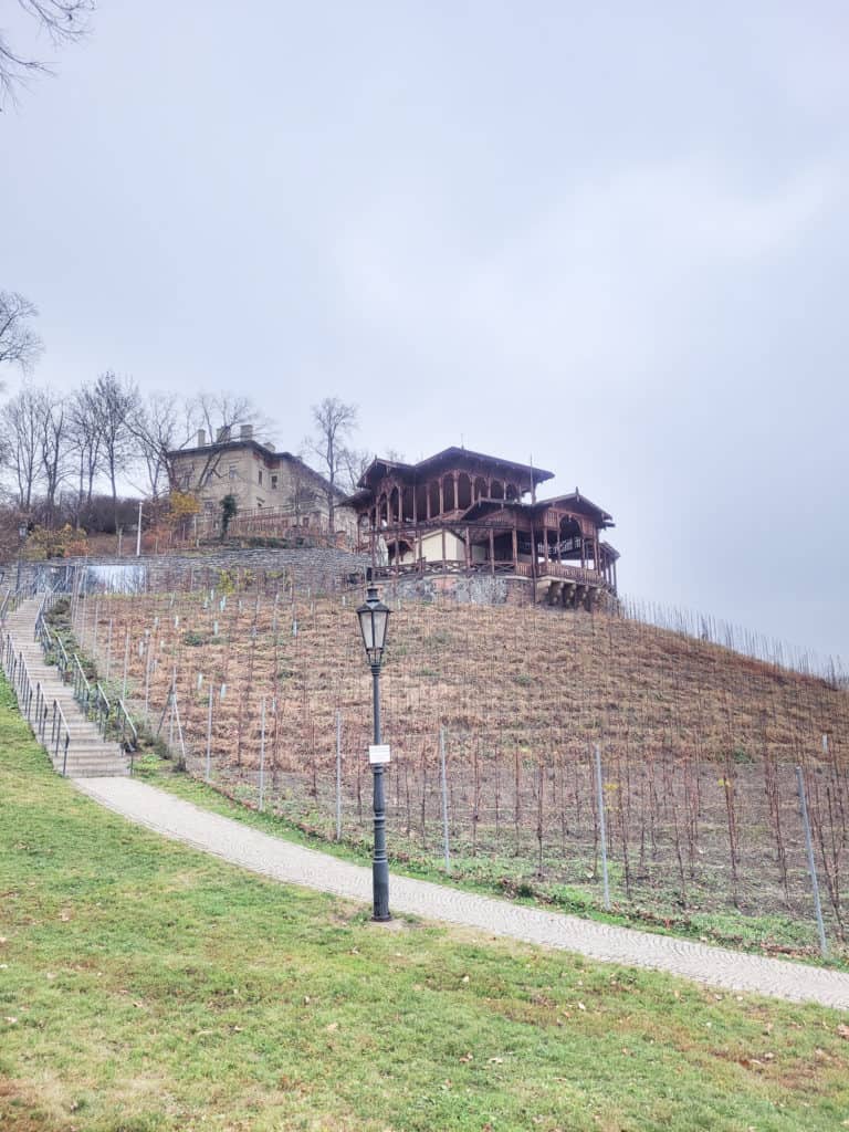 A view of a park with a chalet on the hill and a lamp post in the foreground