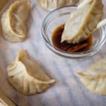 A dumpling being dipped in a soy sauce and vinegar