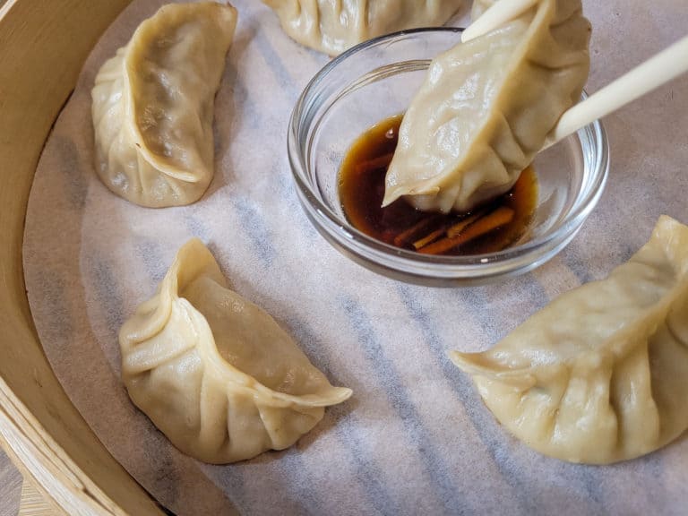 A dumpling being dipped in a soy sauce and vinegar