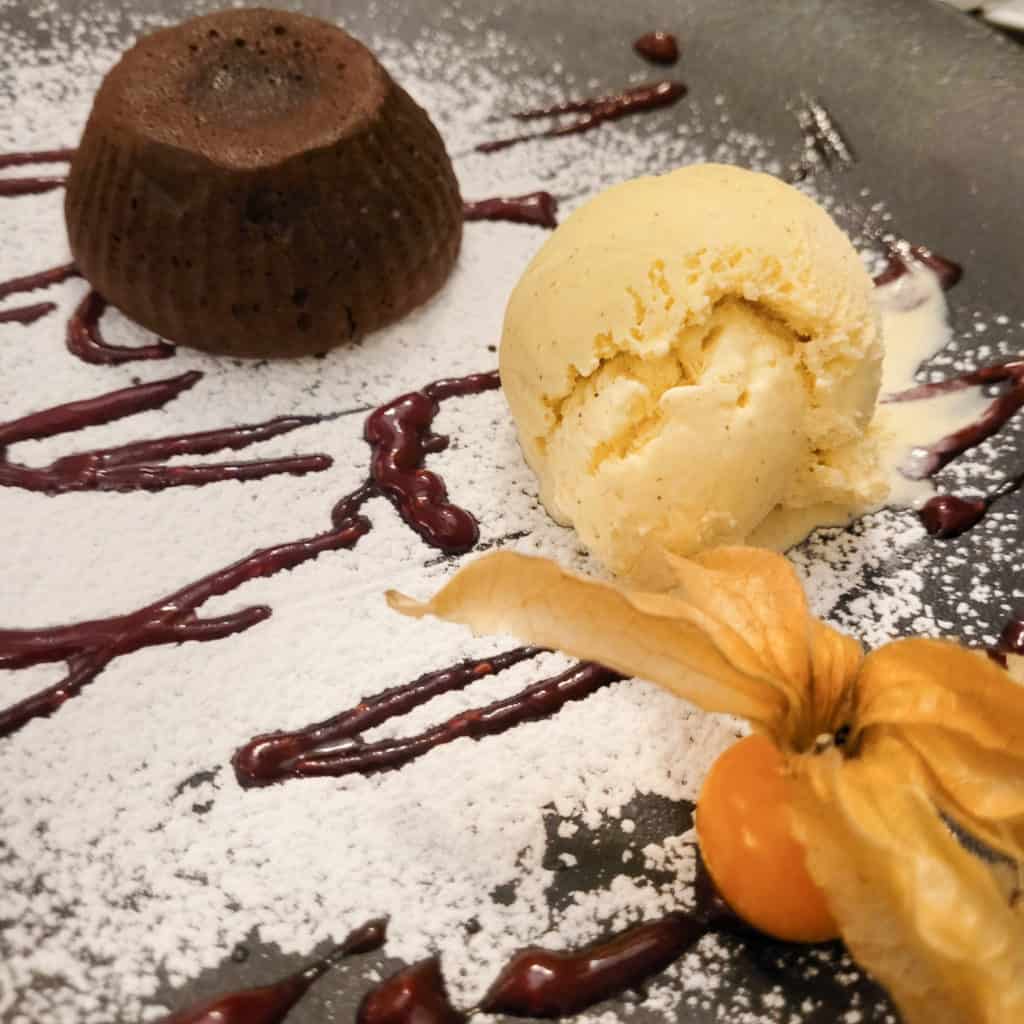 A plate of chocolate lava cake dessert with ice cream with some powdered sugar
