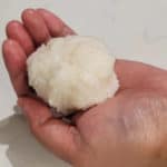 A hand holding a squeezed rice ball
