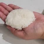 A flattened rice ball in the palm of a hand