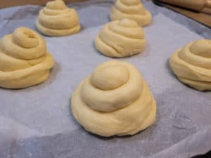 Proofed ensaymada dough on parchment paper in a pan