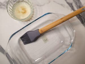 Overhead shot of coconut oil and an empty baking disk with a silicone brush inside