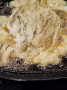 Eggplant on top of fried egg in a cast iron pan