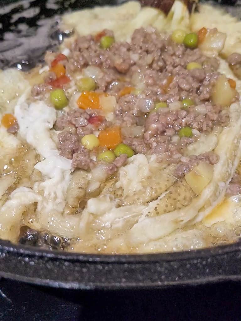 Pork on top of an eggplant omelet in a cast iron