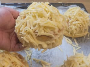 Hand holding an ensaymada in front of other completed buns