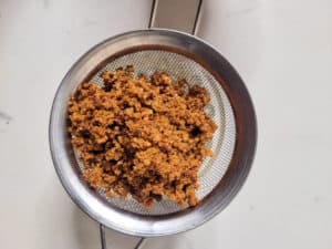 A closeup of latik, cooked coconut cream pieces