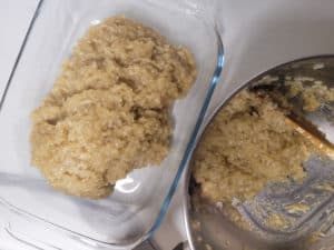 A glass baking dish with some sticky rice next to a silver pot that also has some sticky rice in it