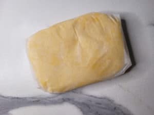 Wrapped tart dough with wax paper on marbled countertop