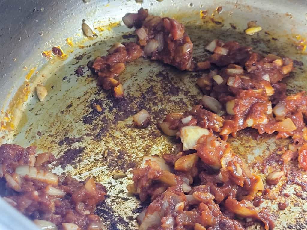 Cooking tomato paste and onions in a pot