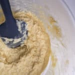 Mixed coconut batter in a bowl with gray spatula