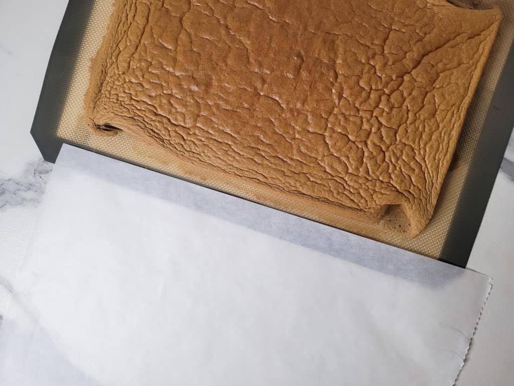 Cooked sponge cake next to clean wax paper
