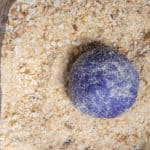 Purple dough rolled in a container of breadcrumbs