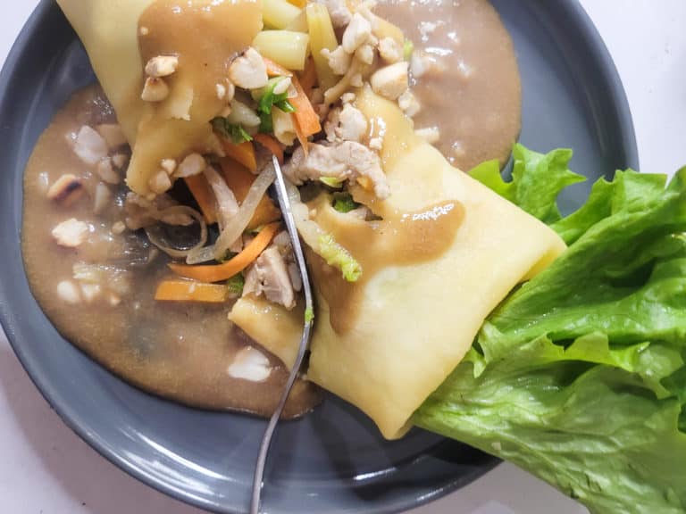 Lumpiang sariwa on a gray plate split in half with a fork