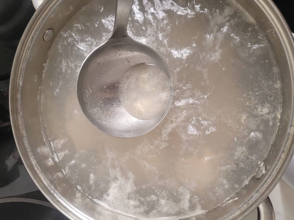 Ladle skimming scum in pot of boiling water