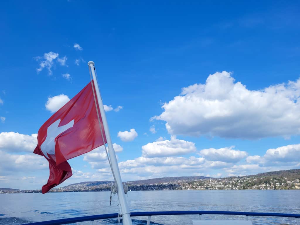 A Swiss flag flowing in the wind on the back of a boat