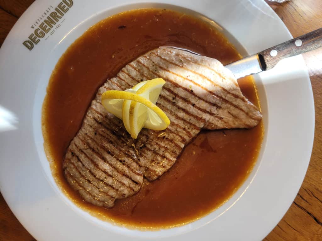 Overhead view of veal cutlet in sauce on a white plate