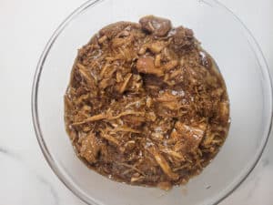 Shredded pork in adobo sauce inside a clear bowl