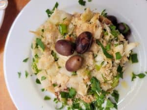 Codfish with cornbread topped with black olives