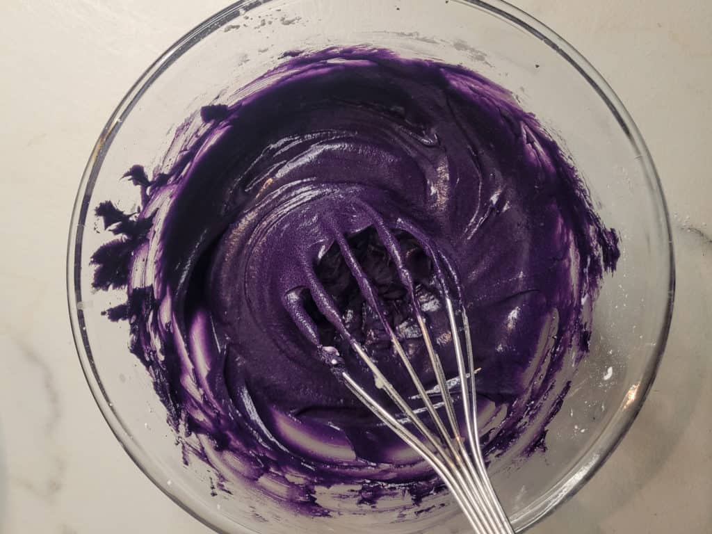 Ube cinnamon roll frosting in a clear bowl
