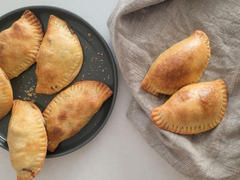 Empanadas on a gray plate next to empanadas on a towel