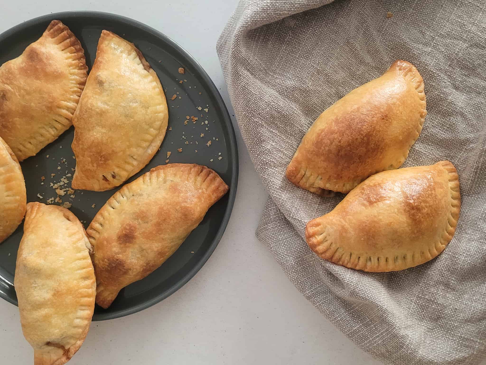 Empanadas on a gray plate next to empanadas on a towel