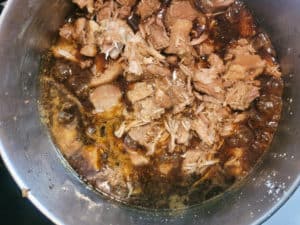 Overhead of thickened sauce with shredded meat
