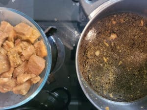 Bowl of browned pork next to a pot of sauce
