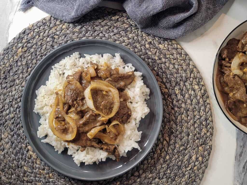 Bistek tagalog or Filipino beefsteak on top of rice
