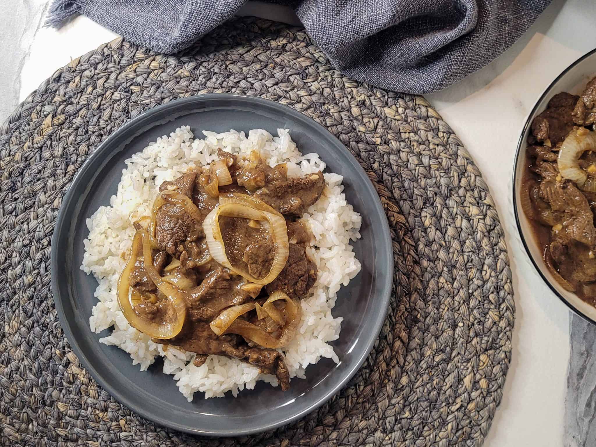 Bistek tagalog or Filipino beefsteak on top of rice