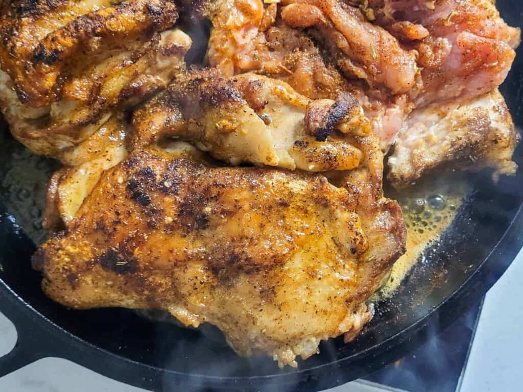 Close up of pan fried chicken thigh in cast iron