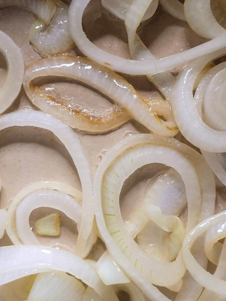 Cooked and softened onion rings in a pan