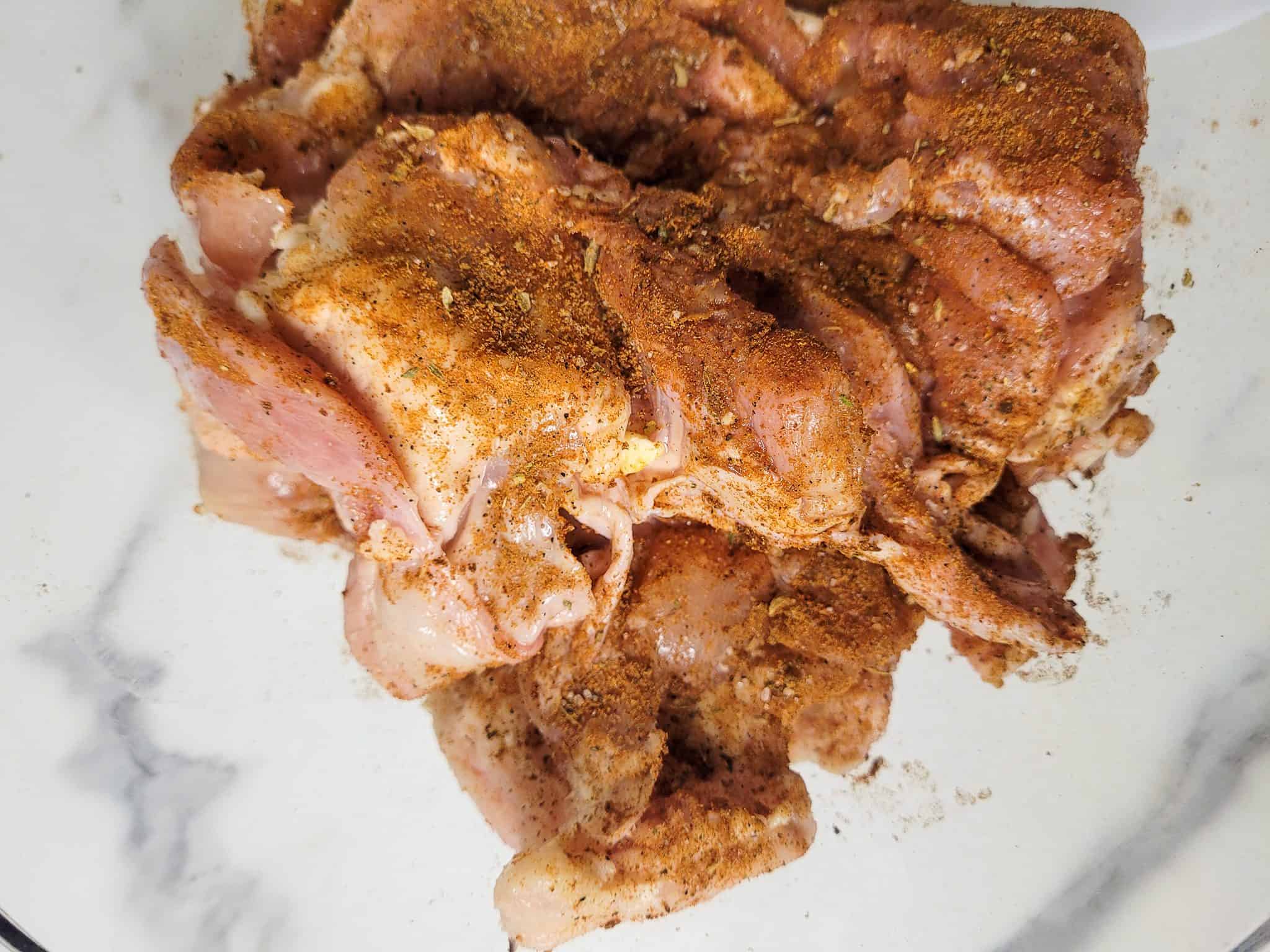 Raw seasoned chicken in glass bowl