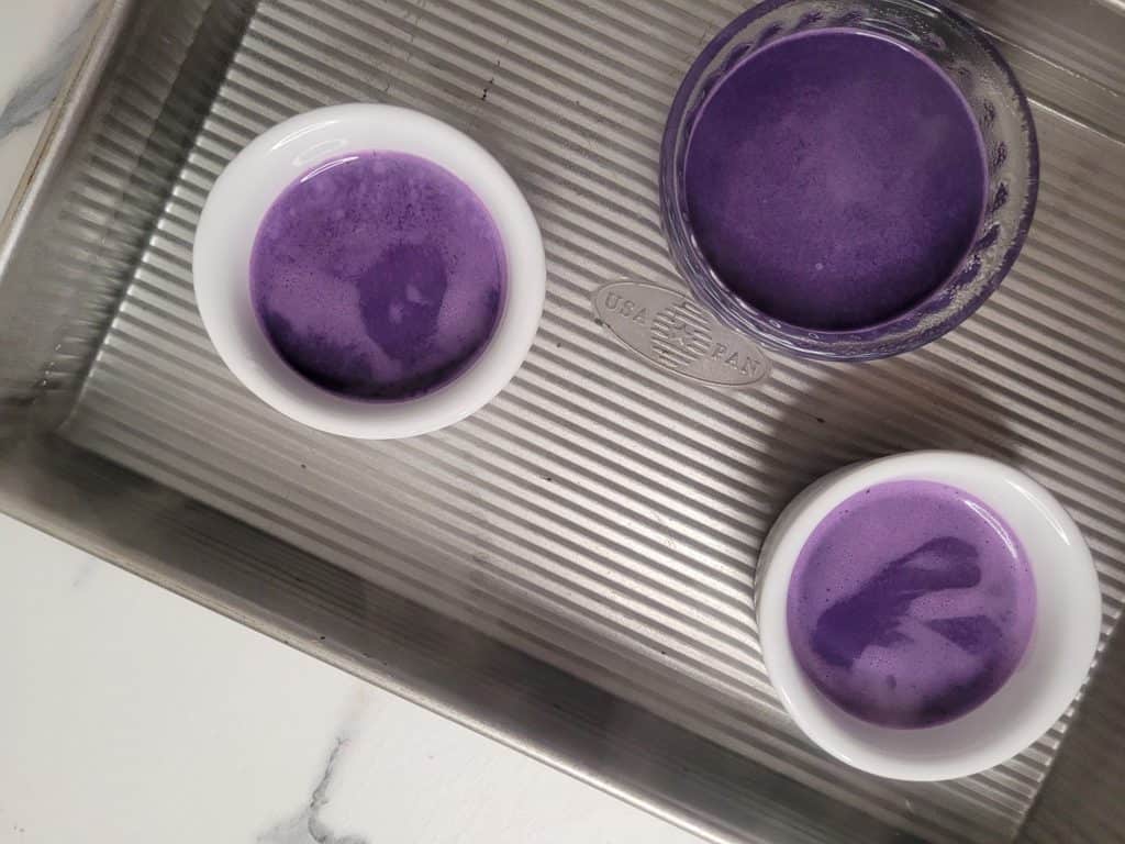 Overhead shot of ramekins filled with ube post de creme liquid custard