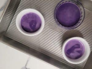 Overhead shot of ramekins filled with ube post de creme liquid custard