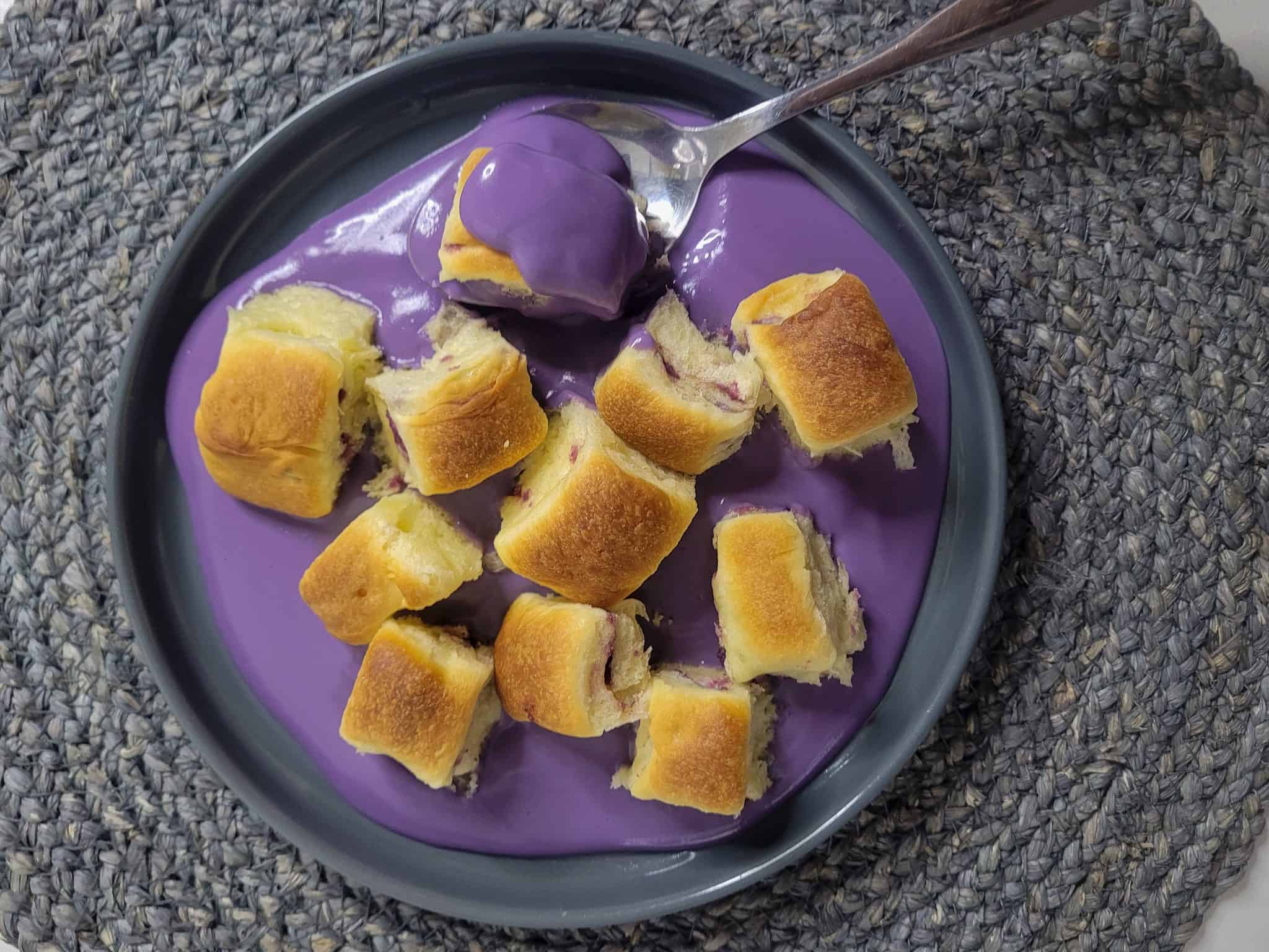 A gray plate with ube mini buns and ube cream sauce