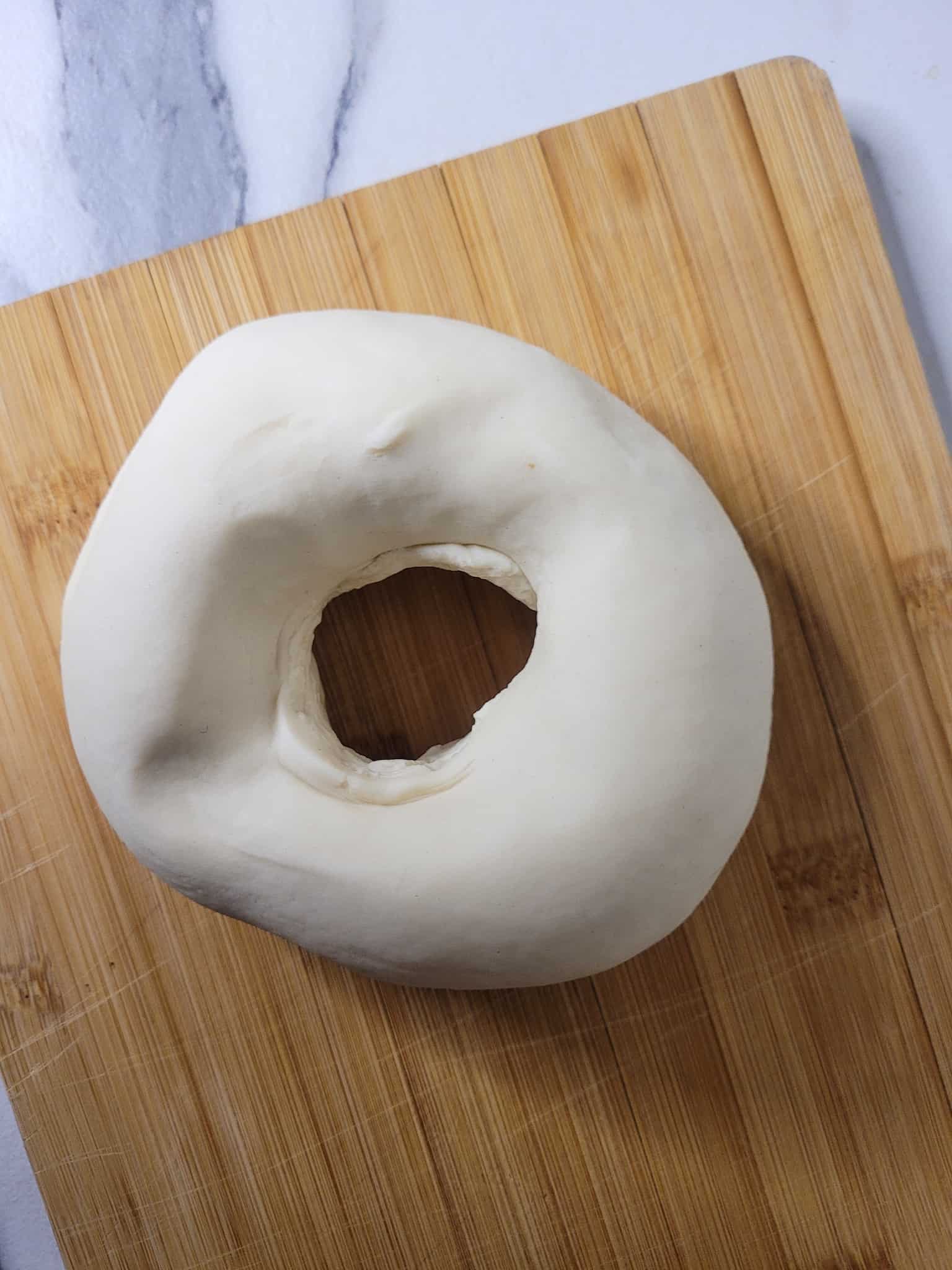 Dough shaped like a donut on top of a wooden board