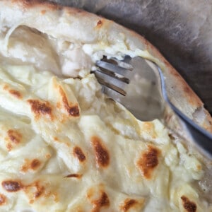 Scoop out excess dough on the side of khachapuri with a fork