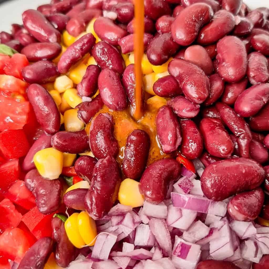 Pouring vinaigrette on top of beans