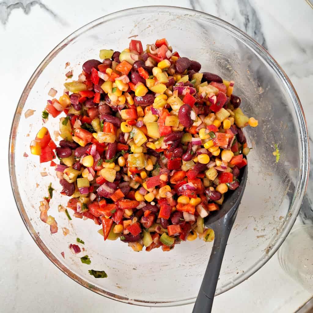 A glass bowl with mixed cowboy caviar and a spatula