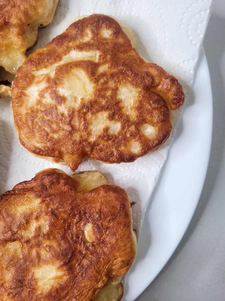 Fried apple fritters on a paper towel line plate