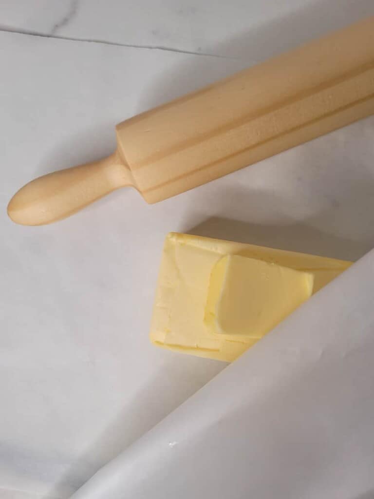 Butter in wax paper next to a rolling pin