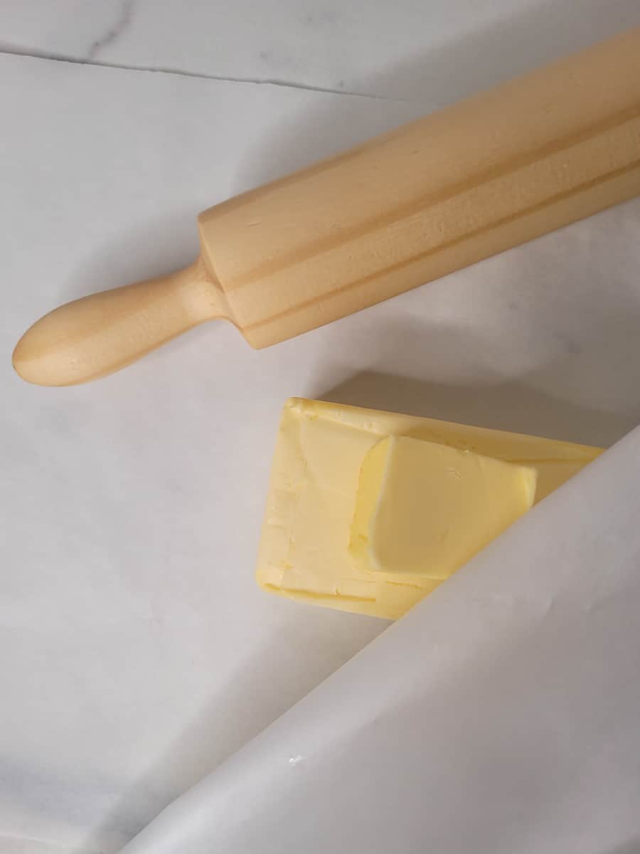 Butter in wax paper next to a rolling pin