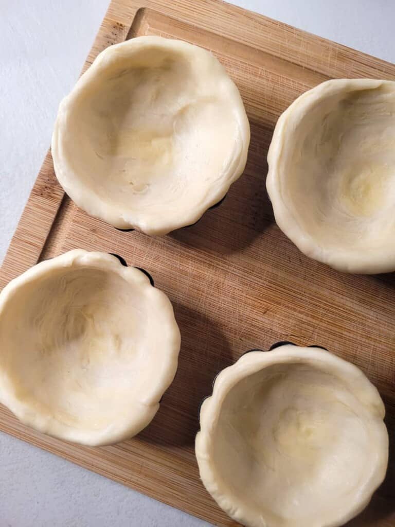 Overhead of prepared tart molds on a wooden board