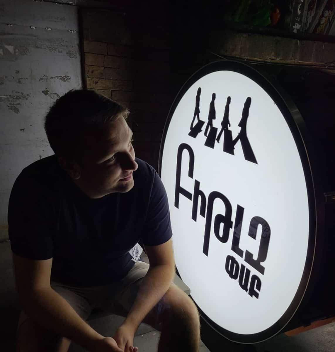 Man sitting in front of a Beatles Sign in Armenian